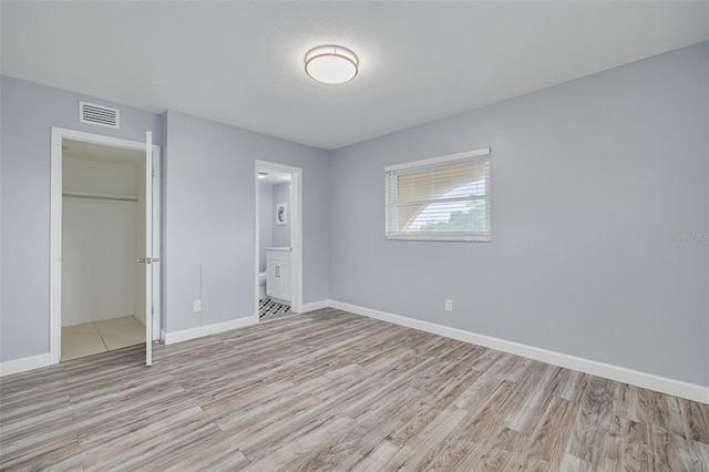 2525 W Bay Dr Unit A46, Largo, FL 33770 - unfurnished bedroom with light wood-style flooring, a closet, and ensuite bathroom
