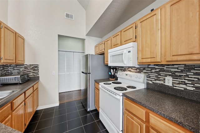 6017 Westgate Dr Unit 924, Orlando, FL 32835 - kitchen with white appliances, dark countertops, light brown cabinets, dark tile patterned flooring, and tasteful backsplash