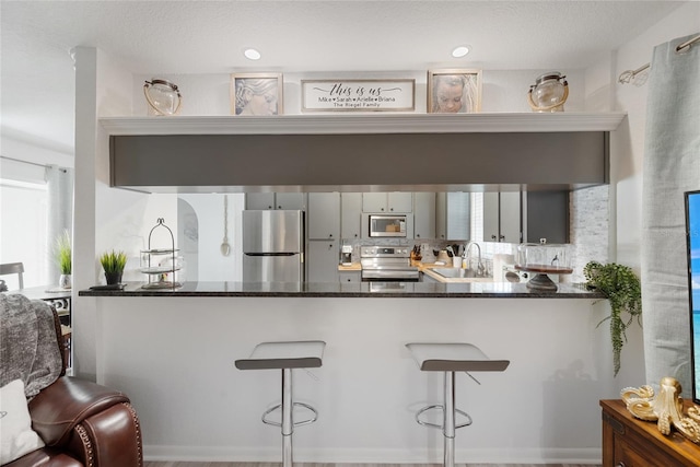 1711 N Highland Ave, Clearwater, FL 33755 - kitchen with appliances with stainless steel finishes, a peninsula, dark stone countertops, and a kitchen bar