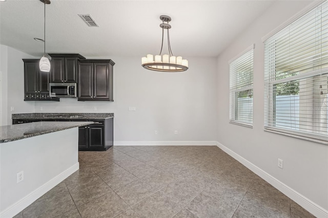 6706 Riverside Bluffs Dr, Riverview, FL 33578 - kitchen featuring stainless steel microwave, a chandelier, dark stone counters, decorative light fixtures, and tile patterned floors