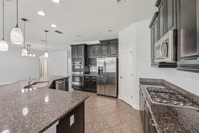 6706 Riverside Bluffs Dr, Riverview, FL 33578 - kitchen featuring appliances with stainless steel finishes, a textured ceiling, dark stone counters, pendant lighting, and light tile patterned flooring