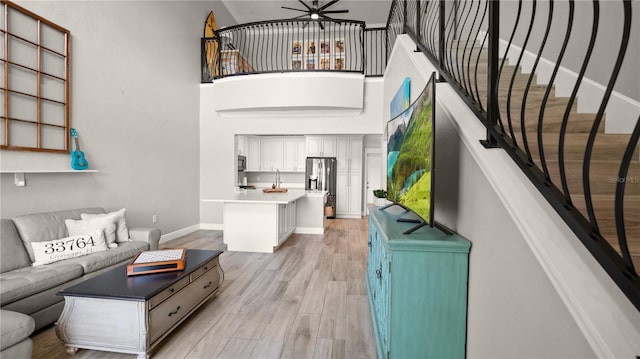 2741 Via Cipriani Unit 916A, Clearwater, FL 33764 - living room featuring light wood-style floors, ceiling fan, stairway, and a high ceiling