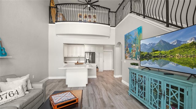 2741 Via Cipriani Unit 916A, Clearwater, FL 33764 - living room featuring a high ceiling, arched walkways, light wood-type flooring, and a ceiling fan