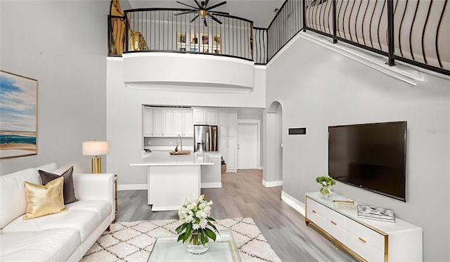 2741 Via Cipriani Unit 916A, Clearwater, FL 33764 - living area featuring arched walkways, a towering ceiling, light wood-style flooring, and ceiling fan