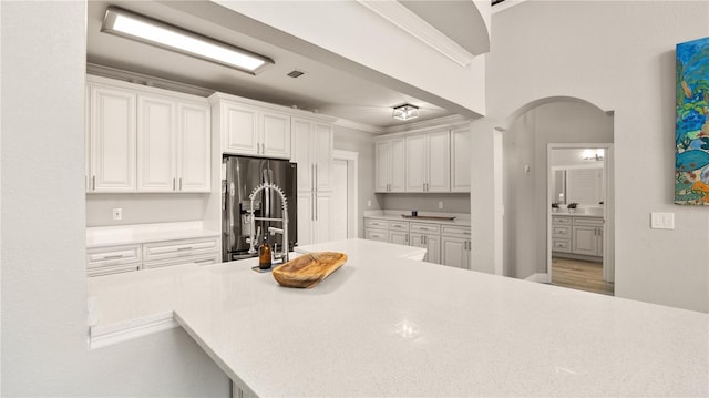 2741 Via Cipriani Unit 916A, Clearwater, FL 33764 - kitchen with stainless steel refrigerator with ice dispenser, white cabinets, light countertops, arched walkways, and ornamental molding