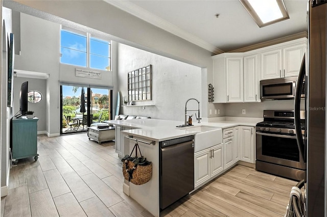 2741 Via Cipriani Unit 916A, Clearwater, FL 33764 - kitchen featuring stainless steel appliances, ornamental molding, light countertops, white cabinets, and light wood-style flooring