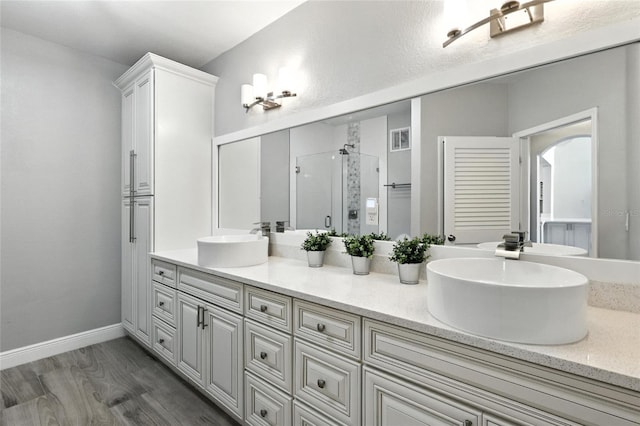 2741 Via Cipriani Unit 916A, Clearwater, FL 33764 - bathroom with double vanity, a shower stall, and wood finished floors