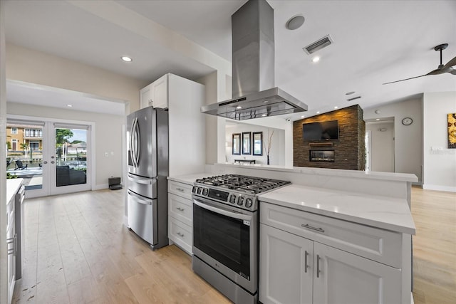 3956 Versailles Dr, Tampa, FL 33634 - kitchen with extractor fan, stainless steel appliances, light stone countertops, a peninsula, and light wood-style flooring