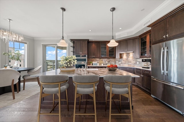 125 Belleview Blvd Unit 503, Belleair, FL 33756 - kitchen with stainless steel appliances, backsplash, dark brown cabinets, ornamental molding, and a kitchen bar
