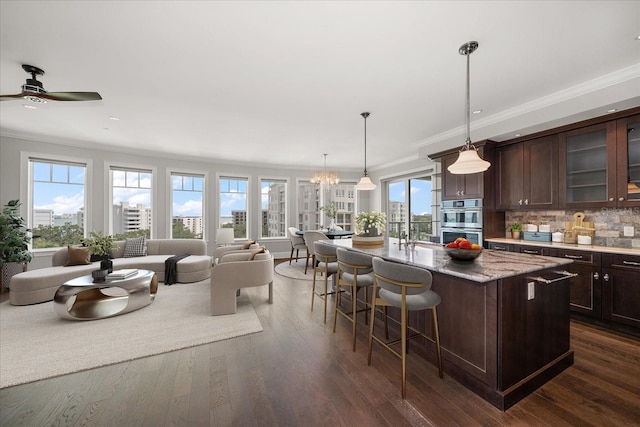 125 Belleview Blvd Unit 503, Belleair, FL 33756 - kitchen with double oven, crown molding, dark brown cabinetry, a kitchen bar, and glass insert cabinets