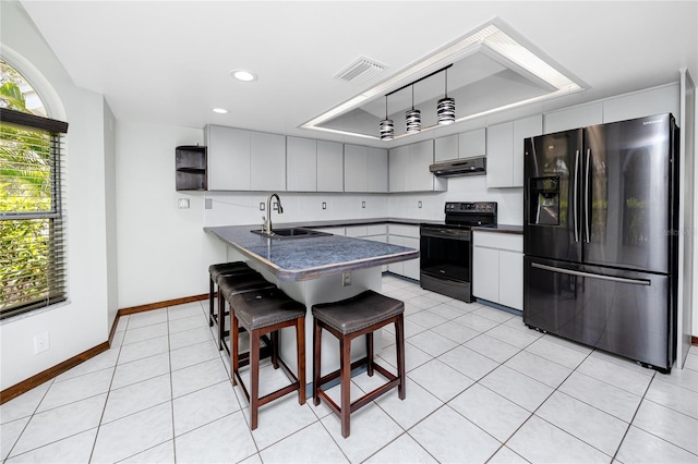 11203 Egret Nest Ct, Riverview, FL 33569 - kitchen with black appliances, dark countertops, under cabinet range hood, a peninsula, and light tile patterned flooring