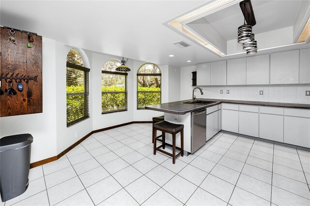 11203 Egret Nest Ct, Riverview, FL 33569 - kitchen with a peninsula, dishwasher, dark countertops, a kitchen bar, and decorative backsplash