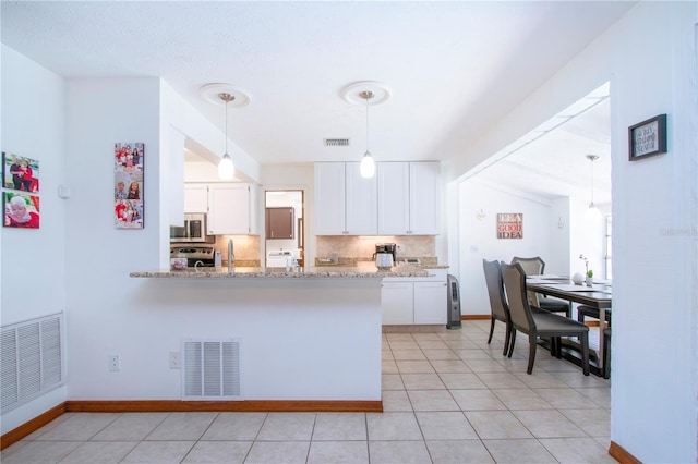4205 Helene Pl, Valrico, FL 33594 - kitchen featuring stainless steel microwave, white cabinets, tasteful backsplash, light stone countertops, and pendant lighting