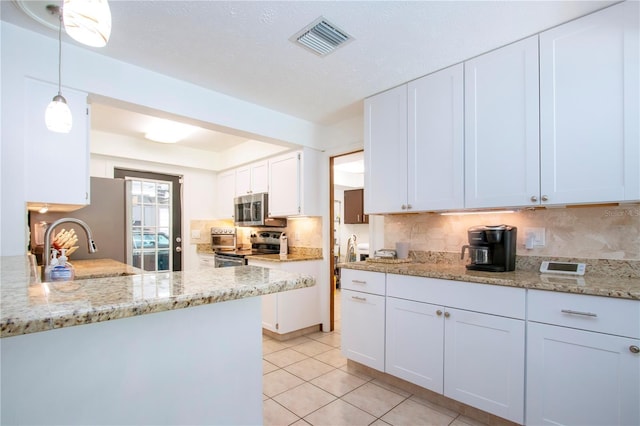 4205 Helene Pl, Valrico, FL 33594 - kitchen with appliances with stainless steel finishes, decorative backsplash, white cabinetry, light tile patterned floors, and light stone countertops