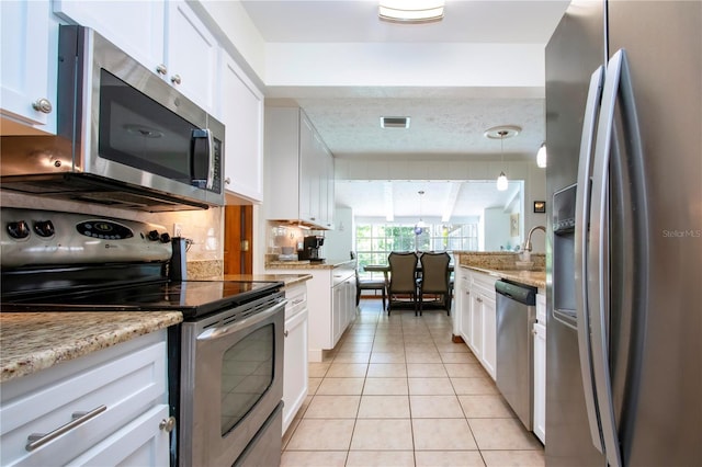 4205 Helene Pl, Valrico, FL 33594 - kitchen with stainless steel appliances, light tile patterned floors, white cabinets, light stone countertops, and pendant lighting