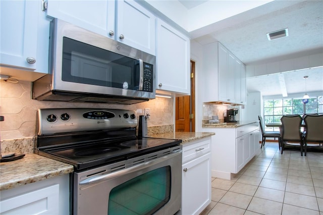 4205 Helene Pl, Valrico, FL 33594 - kitchen with appliances with stainless steel finishes, white cabinetry, light tile patterned floors, backsplash, and a textured ceiling