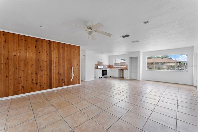 1041 SE Spinnaker Ave, Saint Lucie West, FL 34983 - unfurnished living room featuring a ceiling fan, light tile patterned flooring, and wood walls
