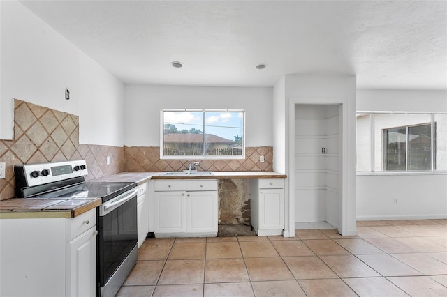 1041 SE Spinnaker Ave, Saint Lucie West, FL 34983 - kitchen with stainless steel electric range oven, white cabinetry, tasteful backsplash, and light tile patterned flooring
