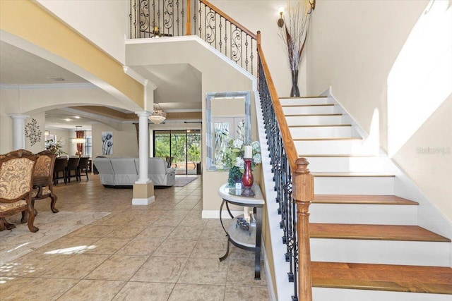 8358 Dunham Station Dr, Tampa, FL 33647 - staircase featuring ornate columns, arched walkways, a towering ceiling, tile patterned flooring, and crown molding