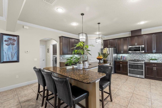 8358 Dunham Station Dr, Tampa, FL 33647 - kitchen with appliances with stainless steel finishes, decorative backsplash, arched walkways, a breakfast bar, and dark brown cabinetry