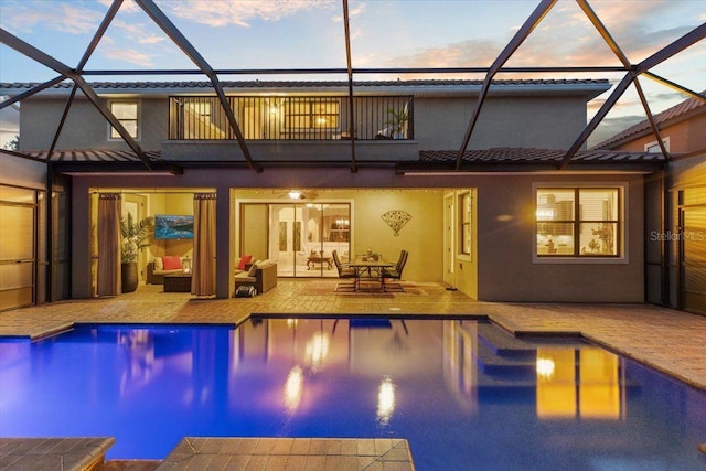 8358 Dunham Station Dr, Tampa, FL 33647 - back of house at dusk with a balcony, stucco siding, a patio area, an outdoor pool, and outdoor lounge area
