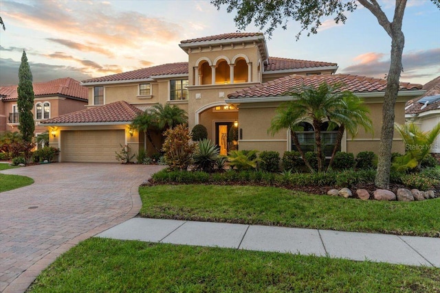 8358 Dunham Station Dr, Tampa, FL 33647 - mediterranean / spanish-style home with an attached garage, decorative driveway, stucco siding, a tiled roof, and a yard