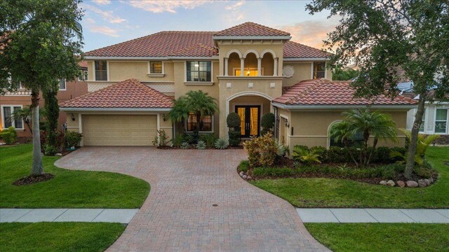 8358 Dunham Station Dr, Tampa, FL 33647 - mediterranean / spanish-style home featuring an attached garage, stucco siding, decorative driveway, a front yard, and french doors