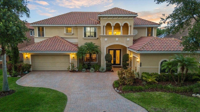 8358 Dunham Station Dr, Tampa, FL 33647 - mediterranean / spanish home featuring a garage, a tiled roof, decorative driveway, stucco siding, and french doors