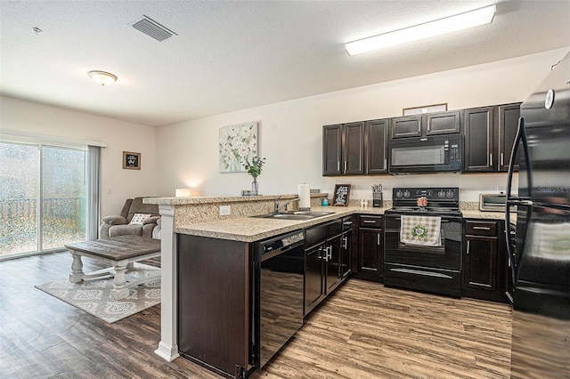 5521 Yellowfin Ct, New Port Richey, FL 34652 - kitchen with black appliances, a peninsula, wood finished floors, light countertops, and a textured ceiling