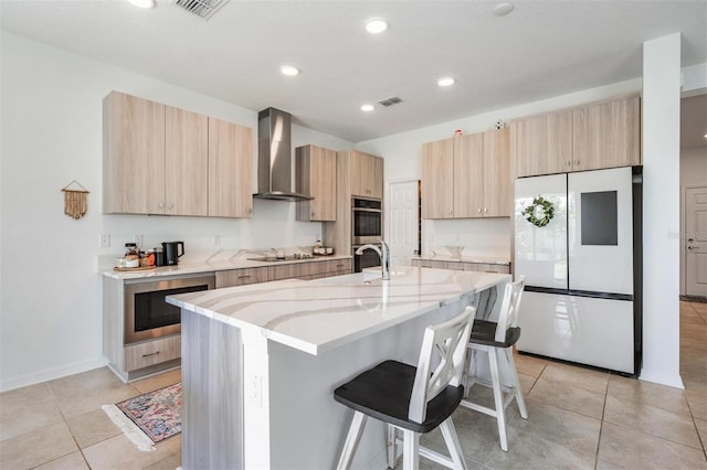 7517 Notched Pine Bnd, Wesley Chapel, FL 33545 - kitchen with wall chimney range hood, freestanding refrigerator, light brown cabinetry, a breakfast bar area, and modern cabinets