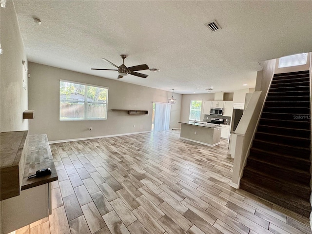 2612 E 26th Ave, Tampa, FL 33605 - unfurnished living room with ceiling fan, stairway, a textured ceiling, and wood tiled floors