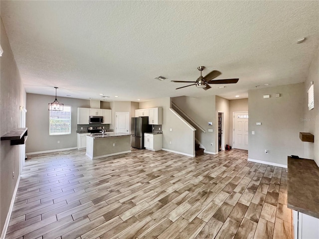 2612 E 26th Ave, Tampa, FL 33605 - unfurnished living room with a textured ceiling, stairs, a ceiling fan, light wood-type flooring, and recessed lighting
