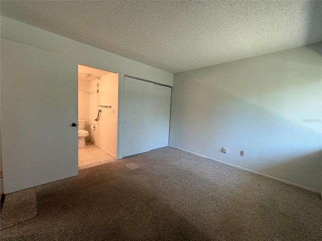 12300 Vonn Rd Unit 9105, Largo, FL 33774 - unfurnished bedroom featuring carpet flooring, a closet, a textured ceiling, and connected bathroom
