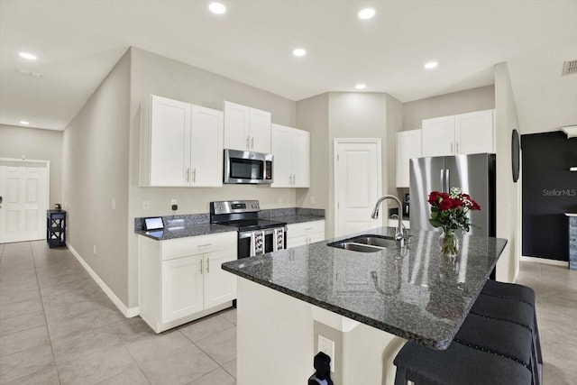 12838 Wildflower Meadow Dr, Riverview, FL 33579 - kitchen with stainless steel appliances, white cabinets, a breakfast bar area, light tile patterned flooring, and an island with sink