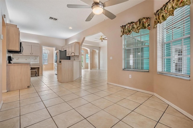 5283 Bevens Ave, Spring Hill, FL 34608 - kitchen featuring arched walkways, ceiling fan, freestanding refrigerator, light tile patterned floors, and light countertops