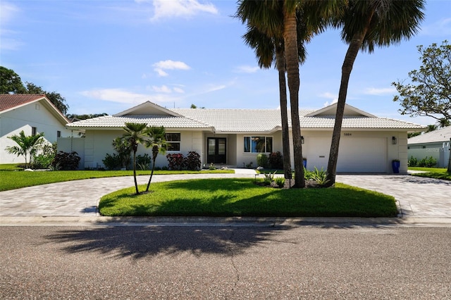 5884 51st St S, Saint Petersburg, FL 33715 - ranch-style home featuring curved driveway, a tiled roof, a front yard, an attached garage, and stucco siding