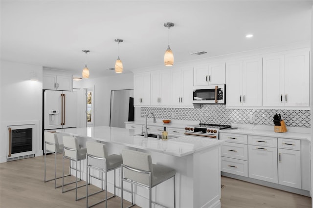 5884 51st St S, Saint Petersburg, FL 33715 - kitchen featuring premium appliances, beverage cooler, decorative backsplash, and white cabinets