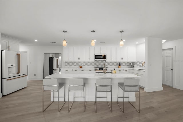 5884 51st St S, Saint Petersburg, FL 33715 - kitchen with high end white fridge, white fridge with ice dispenser, backsplash, white cabinets, and a kitchen breakfast bar