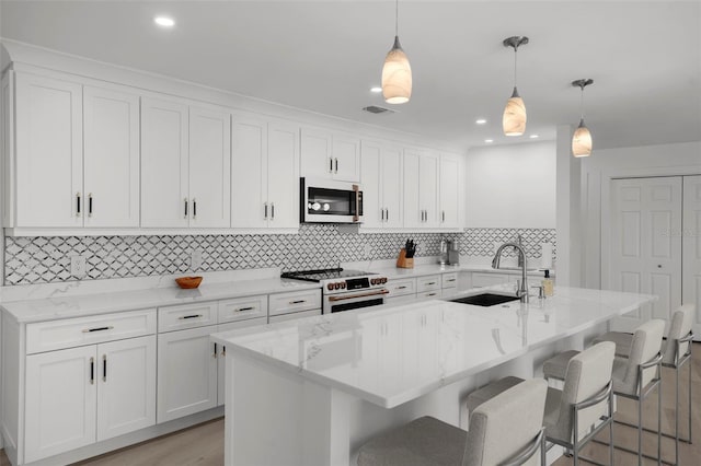 5884 51st St S, Saint Petersburg, FL 33715 - kitchen with high end stainless steel range, light wood-style flooring, white cabinets, tasteful backsplash, and a kitchen island with sink