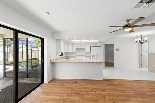 2233 Curlew Rd, Dunedin, FL 34698 - kitchen with white fridge with ice dispenser, range, light wood-style floors, a peninsula, and a textured ceiling