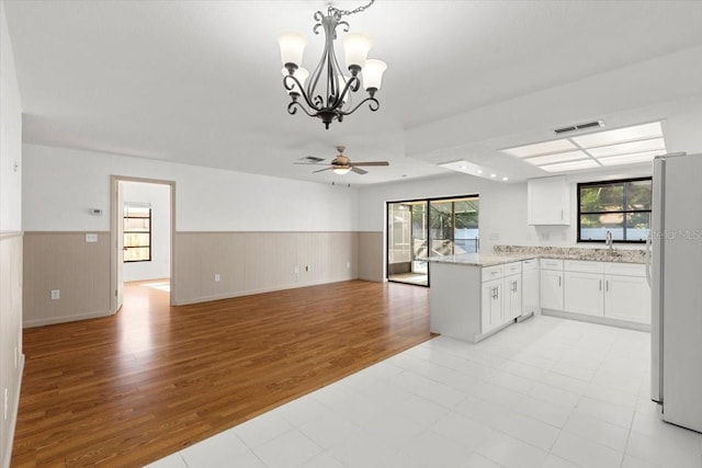 2233 Curlew Rd, Dunedin, FL 34698 - kitchen with freestanding refrigerator, light wood finished floors, healthy amount of natural light, wainscoting, and ceiling fan