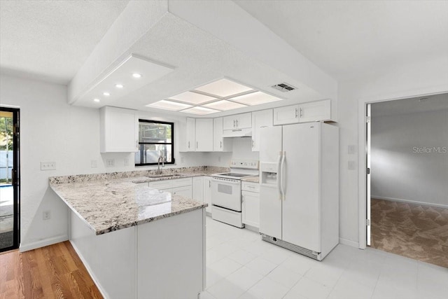2233 Curlew Rd, Dunedin, FL 34698 - kitchen featuring white appliances, a peninsula, light stone countertops, under cabinet range hood, and white cabinetry