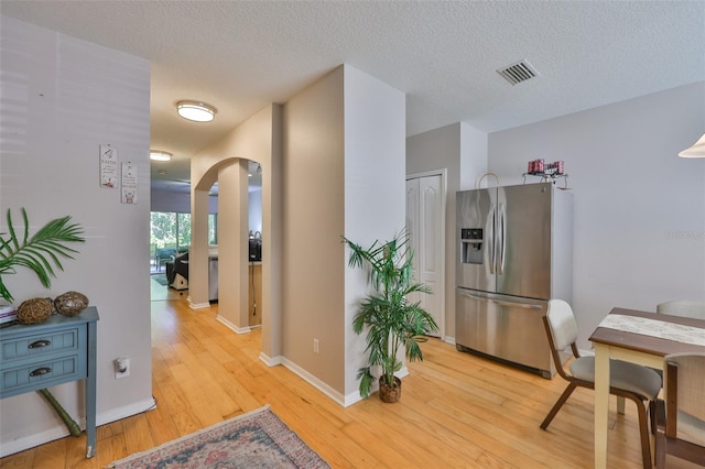 5717 Fishhawk Ridge Dr, Lithia, FL 33547 - kitchen featuring stainless steel fridge, arched walkways, light wood-style flooring, and a textured ceiling