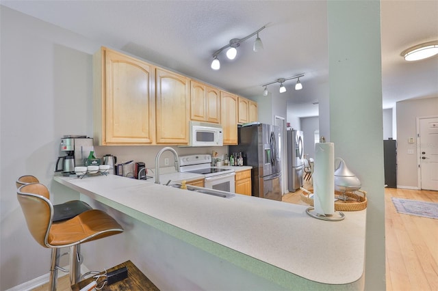 5717 Fishhawk Ridge Dr, Lithia, FL 33547 - kitchen featuring white appliances, light brown cabinetry, light countertops, and light wood finished floors
