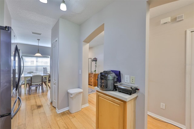 5717 Fishhawk Ridge Dr, Lithia, FL 33547 - kitchen featuring arched walkways, light wood-style flooring, light countertops, pendant lighting, and a textured ceiling