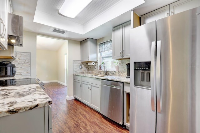 6865 Circle Creek Dr, Pinellas Park, FL 33781 - kitchen featuring stainless steel appliances, a raised ceiling, backsplash, and wood finished floors