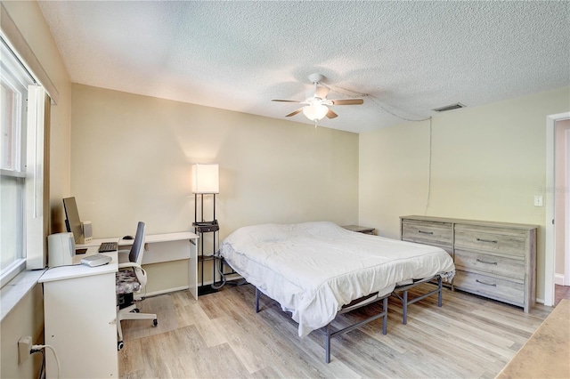 6865 Circle Creek Dr, Pinellas Park, FL 33781 - bedroom with light wood finished floors, a textured ceiling, a desk, and ceiling fan