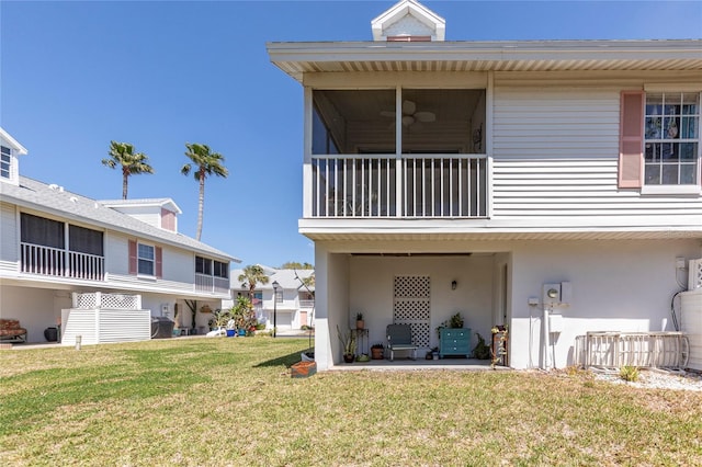 112 Sun Isle Cir Unit 112, Treasure Island, FL 33706 - back of house featuring a balcony, a yard, ceiling fan, and stucco siding