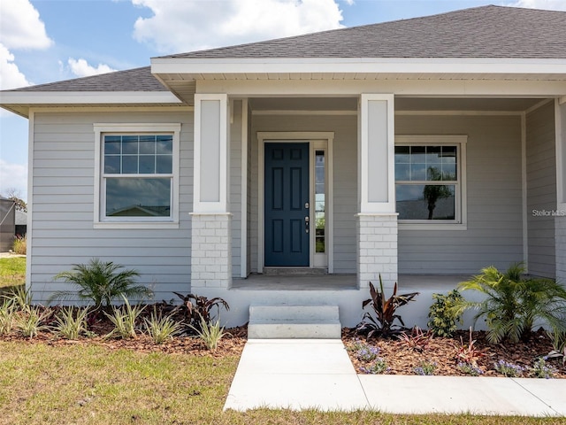 115 White Marsh Ln, Rotonda West, FL 33947 - doorway to property with roof with shingles, brick siding, and covered porch