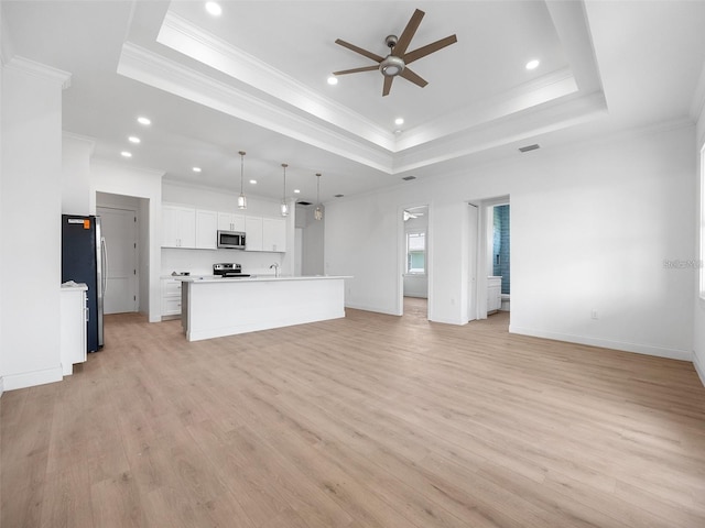 115 White Marsh Ln, Rotonda West, FL 33947 - unfurnished living room featuring a ceiling fan, a tray ceiling, light wood-style floors, recessed lighting, and ornamental molding